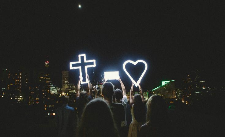 People gathered with an LED light-up cross and heart